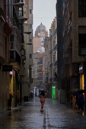 Woman in the middle of a rainy street, protected by her umbrella