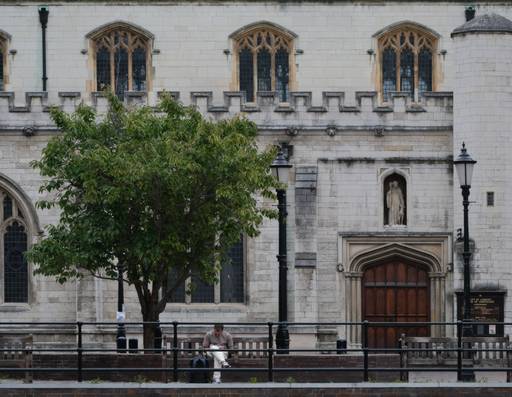 Man sat on a bench reading in front of a church